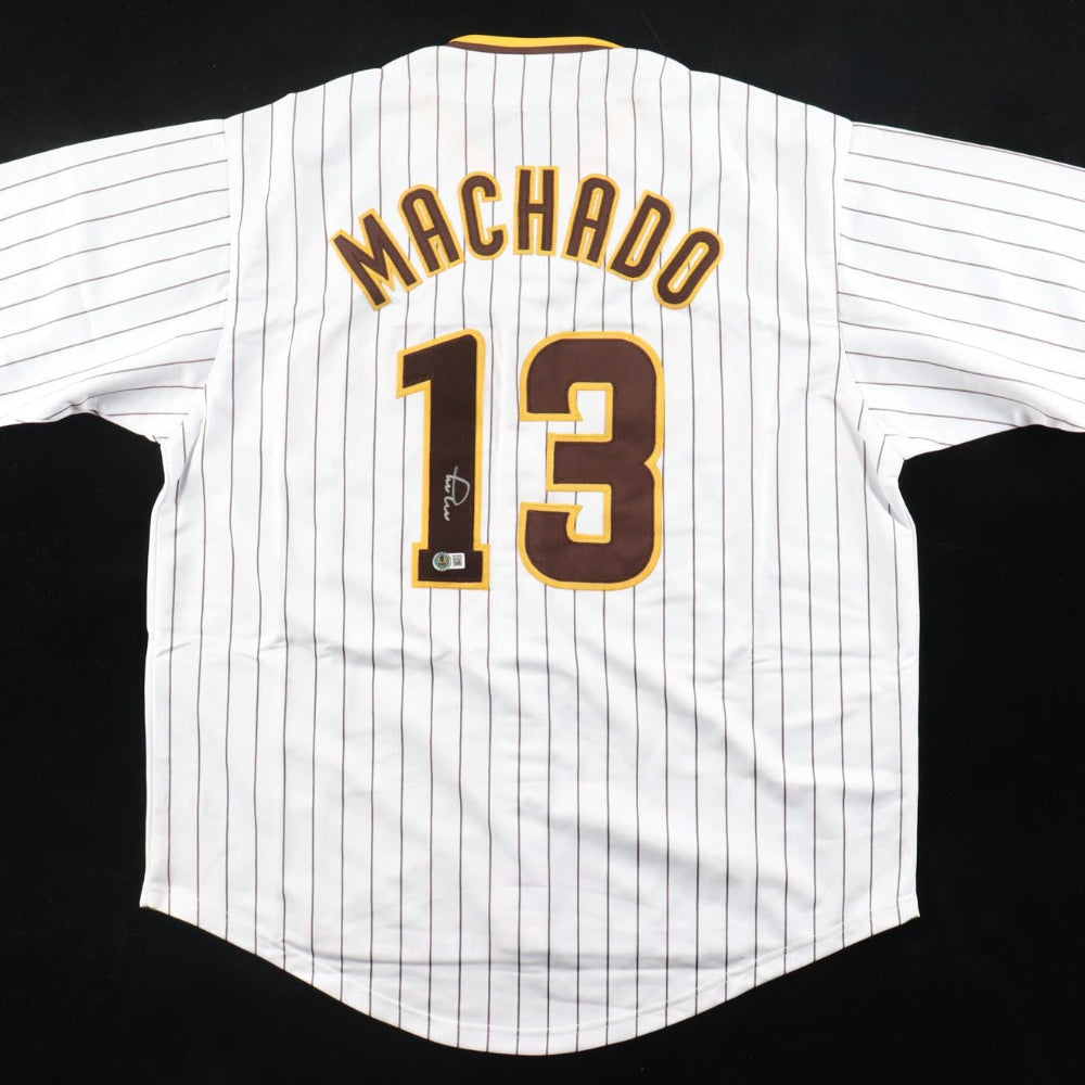 Autographed Baseball jersey with &amp;#39;Machado&amp;#39; and number &amp;#39;13&amp;#39; on a white background