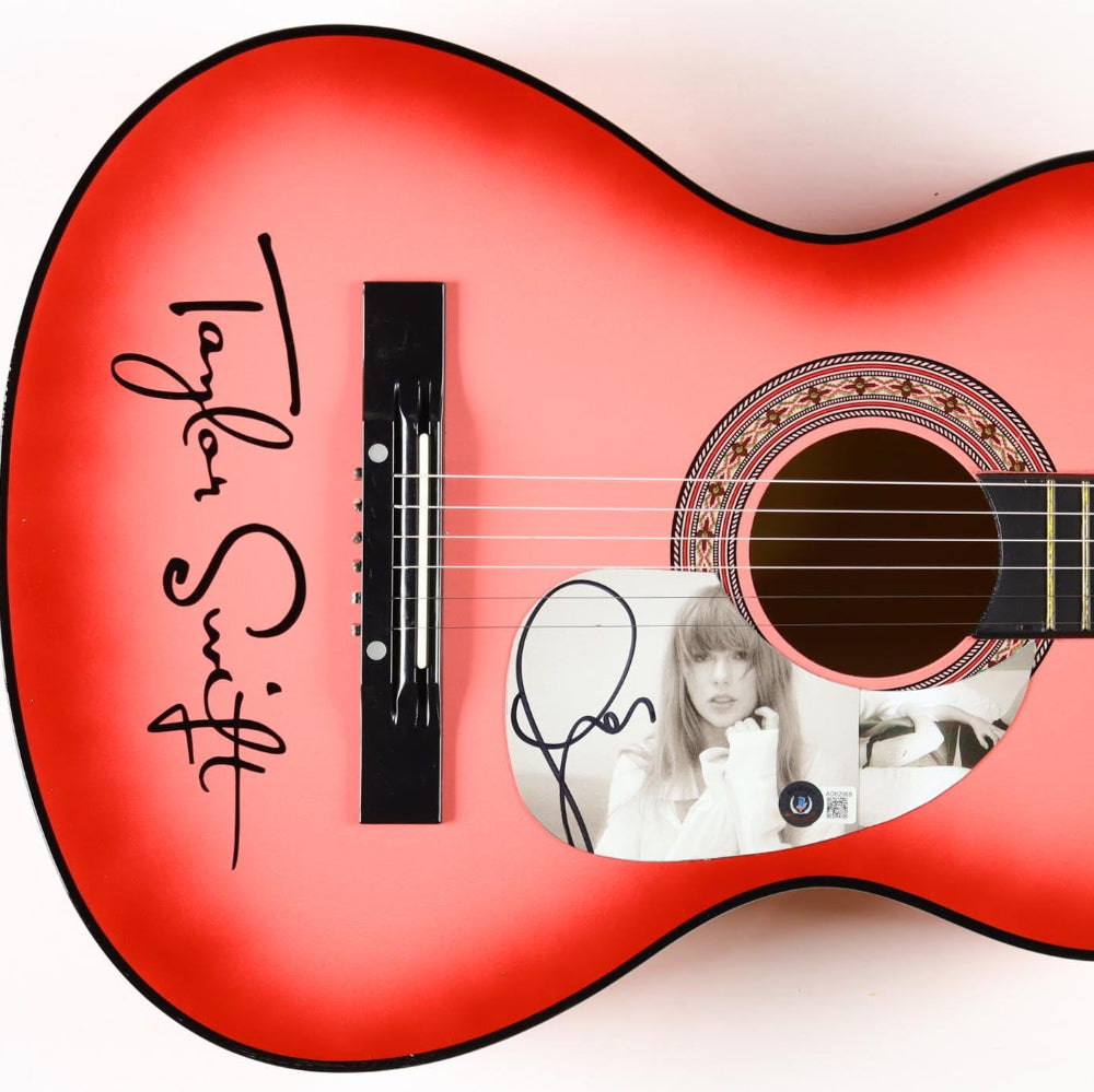 Taylor Swift autographed Red acoustic guitar with a cutout design and signature on a white background